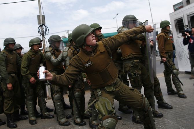 Un policía arroja una lata de gas lacrimógeno durante las protestas en Santiago de Chile. Las calles de Santiago, la capital de Chile, han sido escenario de violentos enfrentamientos entre manifestantes y Carabineros, la fuerza policiaca nacional del país sudamericano. El detonante del caos fue un aumento en las tarifas del metro, que fue suspendido este sábado tras violentas manifestaciones.