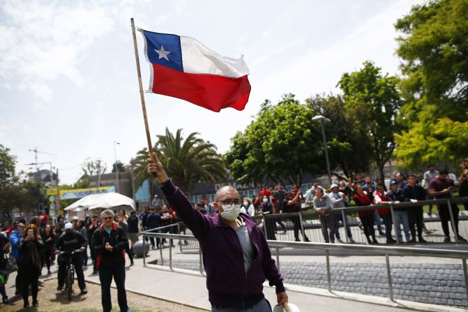 Un manifestante ondea una bandera de Chile a las afueras de la estación de metro Plaza Maipú . El Gobierno justifica el alza de los pasajes del metro debido al precio del dólar y del petróleo, entre otros factores.