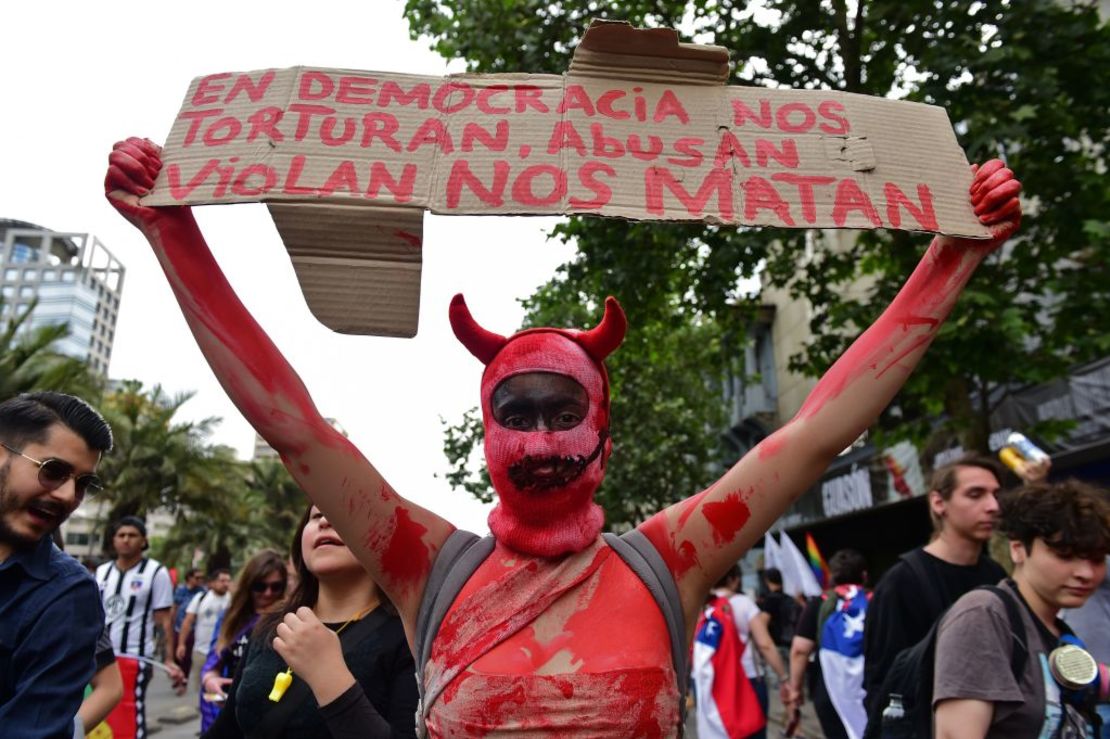 Un manifestante sostiene un cartel que dice "En democracia nos torturan, abusan, violan, nos matan" Foto de Martin BERNETTI / AFP).