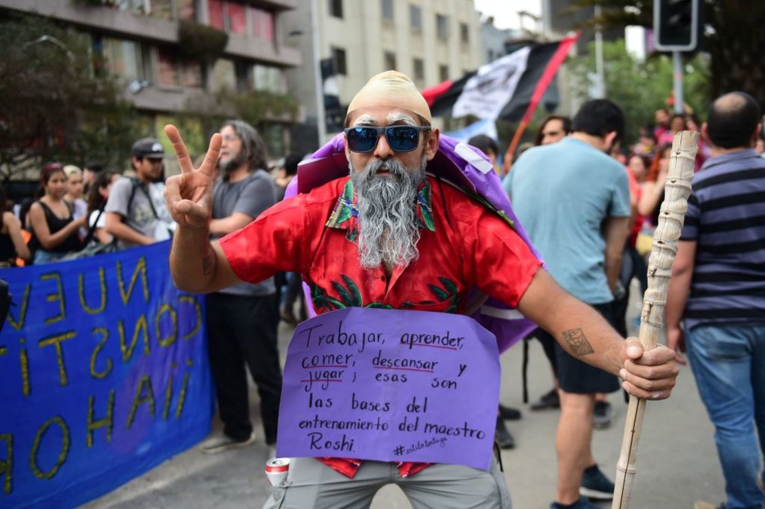 Un hombre usa un disfraza del Maestro Roshi en medio de las manifestaciones de este viernes. Su cartel dice: "trabajar, aprender, comer, descansar y jugar; esas son las bases del entrenamiento del maestro Roshi".