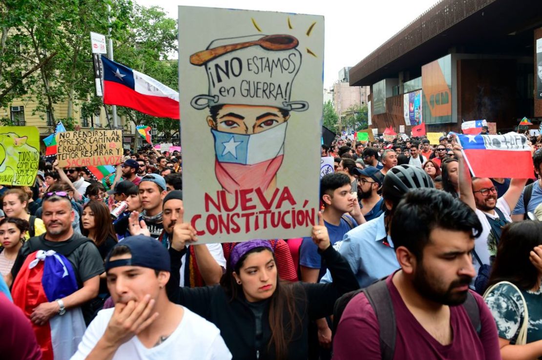 Una mujer lleva un cartel que dice "no estamos en guerra. Nueva Constitución" en Santiago, el 25 de octubre de 2019.