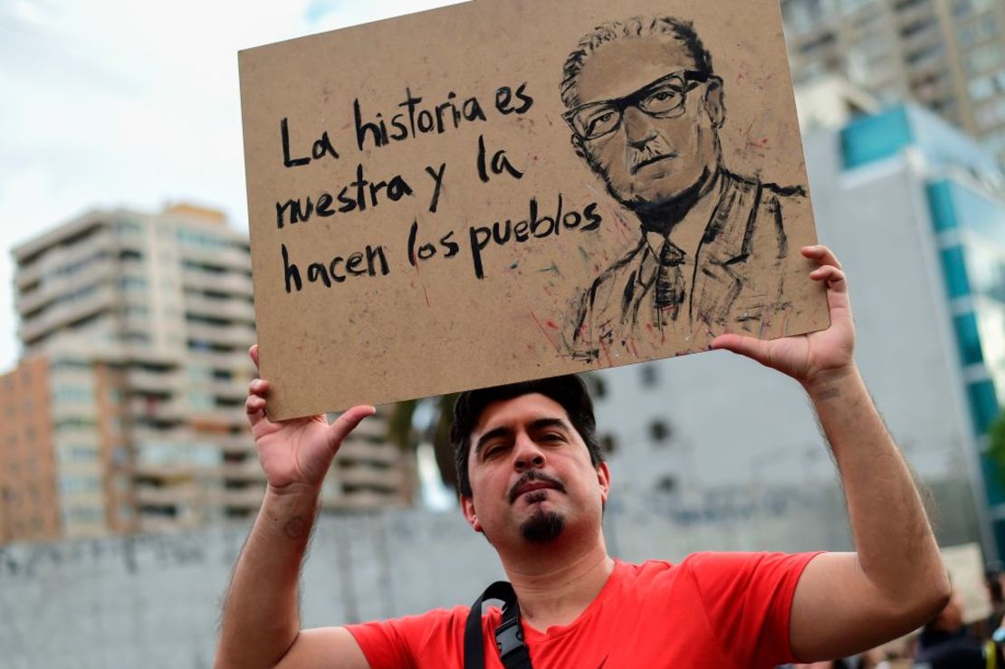 Un hombre sostiene un cartel que representa al fallecido presidente chileno (1970-73) Salvador Allende que dice "La historia es nuestra y la hacen los pueblos".