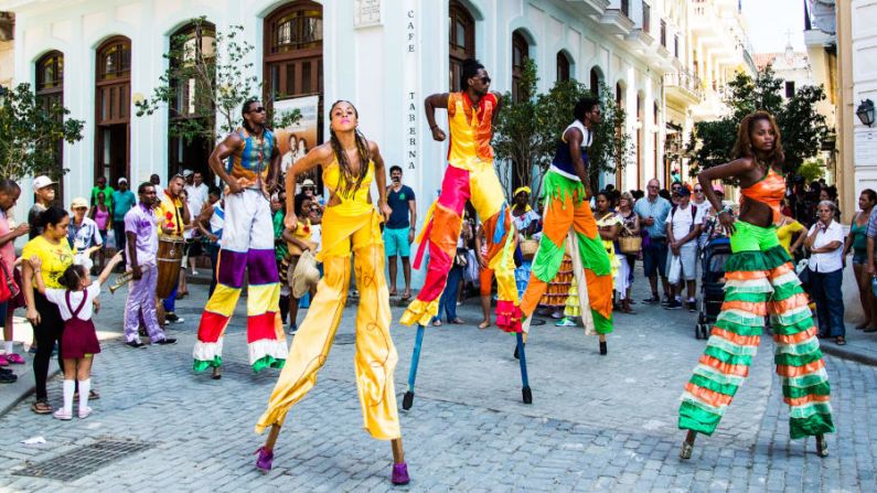 Una banda y un grupo de bailarines en zancos recorren las calles de La Habana Vieja, atrayendo multitudes de visitantes. Aunque los estadounidenses han tratado de normalizar las relaciones con Cuba, los turistas de América del Sur, Canadá y Europa han estado viajado a la isla por generaciones.