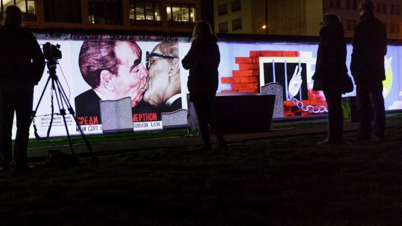 Personas observan una proyección en la East Side Gallery, la Galería del Lado Este, la mayor porción restante del antiguo muro de Berlín, la noche del jueves en la capital alemana, durante una semana de eventos para conmemorar el 30 aniversario de la caída del muro.