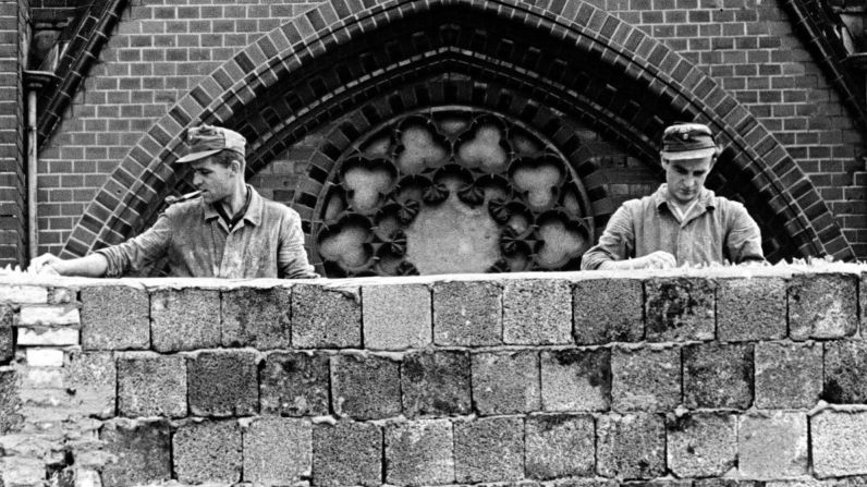 Trabajadores de Alemania Oriental incrustan vidrios rotos en la parte superior del Muro de Berlín el 22 de agosto de 1961, poco después de que comenzara su construcción. Kreusch/AP