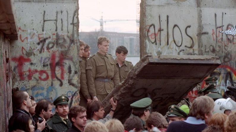 Guardias fronterizos de Alemania Oriental aparecen en una brecha en el Muro después de que los manifestantes derribaron un segmento de la barrera, el 11 de noviembre de 1989. Lionel Cironneau/AP