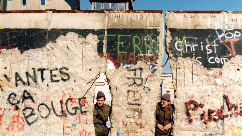 Guardias fronterizos de Alemania Oriental miran a través del muro dañado, cerca del Checkpoint Charlie, en febrero de 1990. Manfred Uhlenhut/dpa/picture-allianc/AP