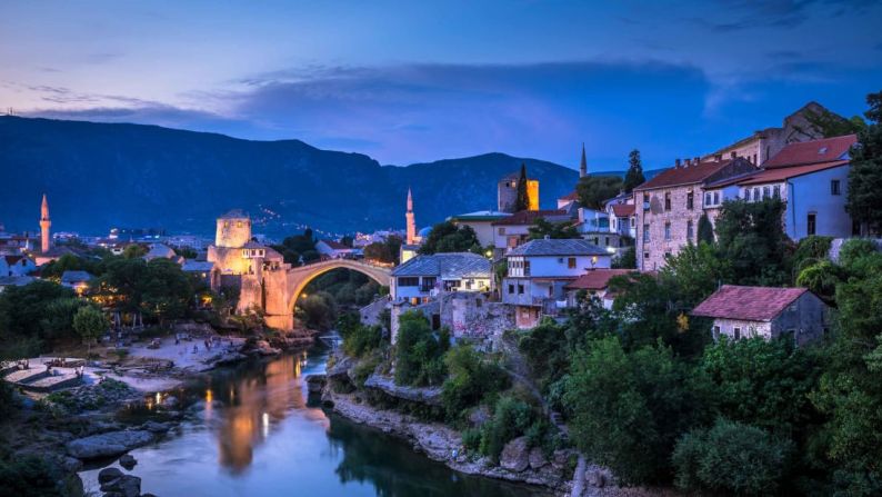 CIUDAD -- Mostar, Bosnia y Herzegovina: Vista nocturna de la ciudad al lado del río donde se ve el puente Stari Most.