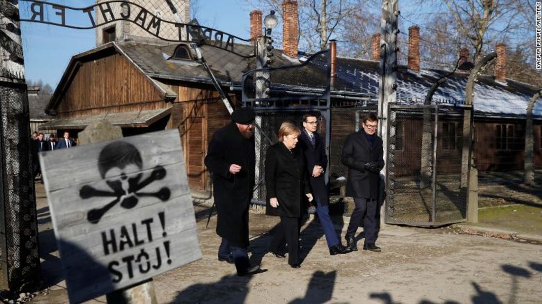 La canciller de Alemania Angela Merkel, el primer ministro de Polonia, Maeusz Morawiecki, y el director del museo Piotr Cywinski, caminan por la puerta "Arbeit Macht Frei" en el antiguo campo de concentración nazi de Auschwitz en Oswiecim, Polonia, el 6 de diciembre de 2019.