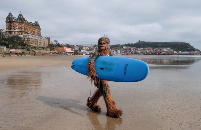 6 de abril: Will Hyde, vestido con un disfraz de Chewbacca, lleva una tabla de surf a través de una playa en Scarborough, Inglaterra. La ciudad fue anfitriona de un evento de ciencia ficción durante el fin de semana.