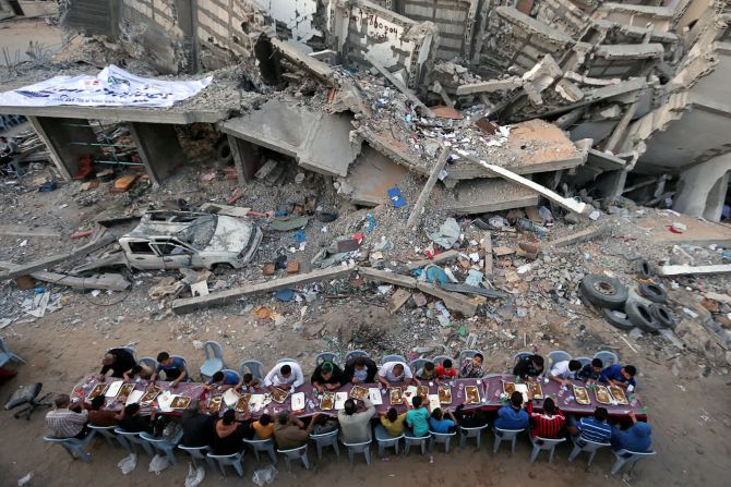 18 de mayo: Un grupo de personas en la ciudad de Gaza interrumpe su ayuno del Ramadán cerca de un edificio que fue destruido recientemente por un ataque aéreo israelí.