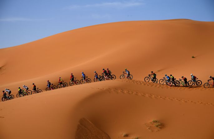 Competidores montan sus bicicletas de montaña a lo largo de las dunas de arena durante la carrera Titan Desert en Marruecos el 28 de abril.