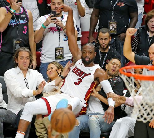 El jugador profesional de baloncesto Dwyane Wade aterriza sobre el cantante John Legend y la modelo Chrissy Teigen durante un partido de la NBA en Miami el 9 de abril. Charles Trainor Jr./Miami Herald / TNS / Newscom