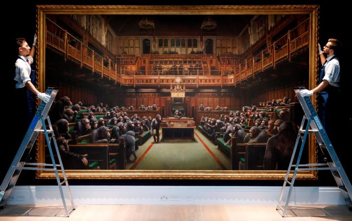 27 de septiembre: asistentes posan con la pintura de Banksy "Devolved Parliament" en la casa de subastas Sotheby's en Londres. La obra de arte, que muestra los bancos del Parlamento ocupados por primates, se vendió en una subasta por un récord de £ 9.879.500 ($ 12.200.000).