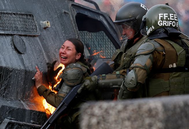 4 de noviembre: un agente de policía reacciona después de ser golpeada con una bomba molotov durante las protestas en Santiago, Chile. Dos mujeres policías, María José Hernández Torres y Abigail Catalina Aburto Cárdenas, se incendiaron después de ser golpeadas con cocteles molotov, informó Reuters. Sus colegas ayudaron a extinguir las llamas, pero las mujeres tuvieron que ser hospitalizadas. Unos días después, la policía le dijo a un corresponsal de Reuters que las mujeres salieron de cuidados intensivos y se recuperaron. Jorge Silva / Reuters