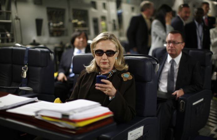 Hillary Clinton, en ese entonces secretaria de Estado de los Estados Unidos, revisa su BlackBerry en un avión militar en octubre de 2011. Clinton dijo que utilizó una cuenta de correo electrónico privada para su trabajo oficial en el Departamento de Estado y que lo hizo por conveniencia. El FBI investigó si Clinton o sus ayudantes habían manejado mal la información clasificada, ya sea intencionalmente o de manera muy negligente. En 2016, el director del FBI James Comey dijo que no recomendaría cargos contra Clinton, pero la reprendió a ella y a sus asesores por ser "extremadamente descuidados" en el manejo de información clasificada.