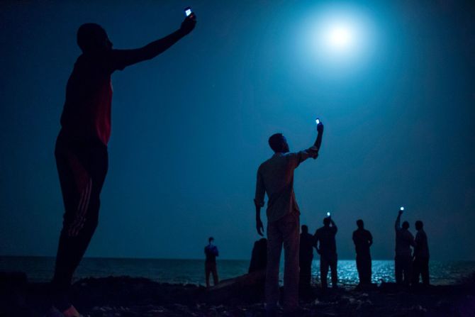 Migrantes africanos en Djibouti levantan sus teléfonos para intentar captar una señal barata de la vecina Somalia en febrero de 2013. Djibouti es un punto de parada común para los migrantes africanos que buscan una vida mejor en Europa y Medio Oriente.