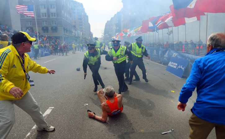 Varios policías se paran sobre el corredor de maratón Bill Iffrig mientras suena una segunda explosión cerca de la línea de meta del Maratón de Boston en abril de 2013. Tres personas murieron y al menos 264 resultaron heridas en el ataque terrorista.