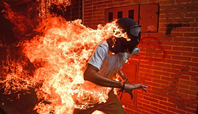 Un manifestante con fuego sobre cuerpo durante las protestas antigubernamentales en Caracas, Venezuela, en mayo de 2017. Ocurrió cuando las personas que protestaban se enfrentaron con la policía y explotó el tanque de gasolina de una moto policial. Otras fotos de la escena muestran al hombre siendo atendido con quemaduras en su cuerpo.