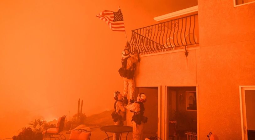 Tres bomberos retiran una bandera estadounidense mientras un incendio forestal amenaza una casa en Oroville, California, en julio de 2017. Los intensos incendios forestales obligaron a miles de personas a evacuar sus hogares en el oeste de Estados Unidos. Científicos señalan una serie de condiciones que han llevado a incendios forestales más letales en los últimos años, todas relacionados con el cambio climático.