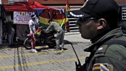 A policeman stands guard as opponents of Bolivian ex-president Evo Morales, exiled in Argentina, camp outside La Rinconada gated community, where the Mexican embassy is located, in La Paz on Dcember 30, 2019. - Bolivia's interim president, Jeanine Anez, announced Monday that the country will expel Mexico's ambassador and two Spanish diplomats, escalating a dispute over an alleged attempt to extract an ex-government aide. (Photo by JORGE BERNAL / AFP)