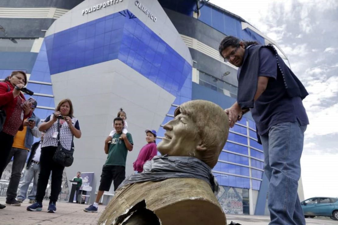 Un grupo de gente se reúne alrededor del busto del expresidente de Bolivia Evo Morales después de que fuera derribado por empleados del Ministerio de Deportes de ese país.