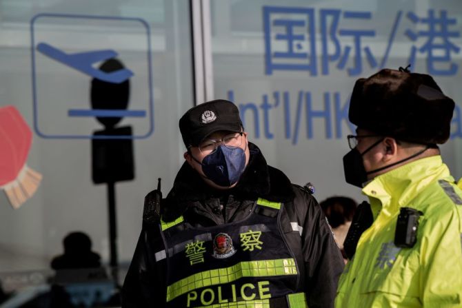 Oficiales de policía usan tapabocas en el Aeropuerto Internacional de Beijing. (Photo by NICOLAS ASFOURI / AFP).