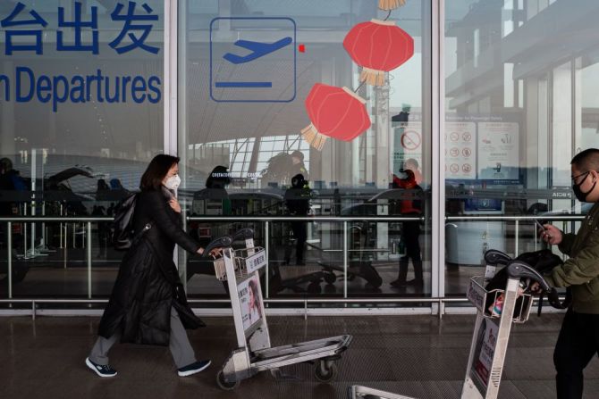 Pasajeros que viajan por el Año Nuevo Chino usan tapabocas en el área de salidas del aeropuerto internacional de Beijing. Photo by NICOLAS ASFOURI / AFP).