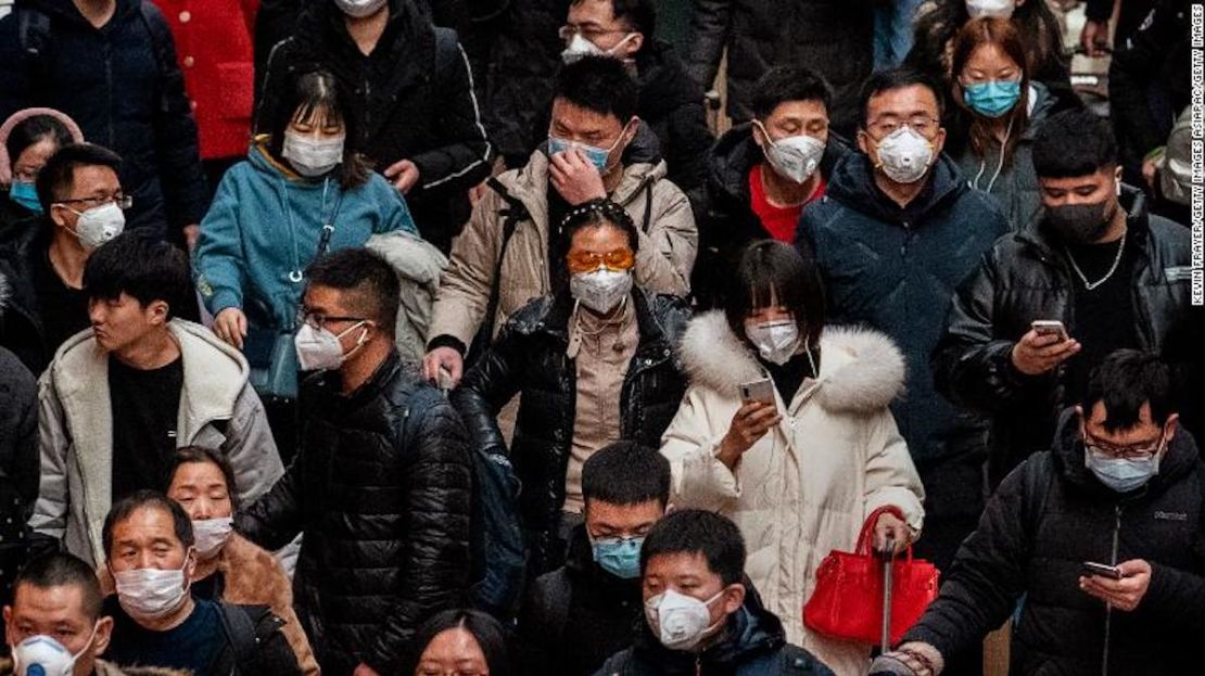 Pasajeros chinos, casi todos llevando tapabocas, llegan a abordar los trenes en la estación central de Beijing antes del festival anual de Primavera el 23 de enero de 2020.