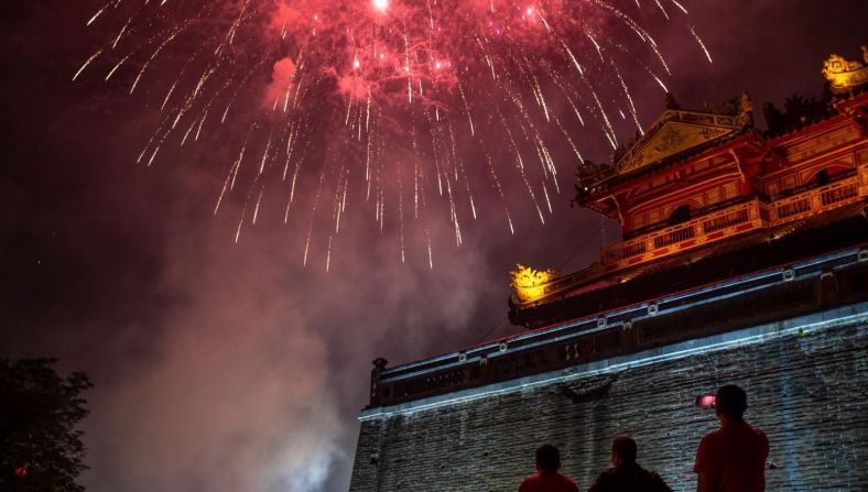 Personas observan fuegos artificiales frente a la Ciudad Imperial de Hue para celebrar el Año Nuevo Lunar en Hue, Vietnam.