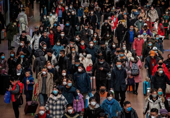 Pasajeros chinos, la mayoría con máscaras faciales, se preparan para abordar los trenes en Beijing el jueves 23 de enero, antes del Festival de Primavera del Año Nuevo Lunar.