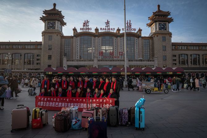 Pasajeros chinos sostienen una pancarta junto a su equipaje frente a la estación de trenes de Beijing el viernes 10 de enero.