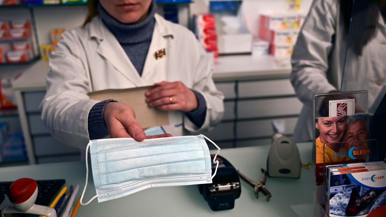 A pharmacist shows a model of mask in a pharmacy of via Paolo Sarpi, the commercial street of the chinese district of Milan on January 30, 2020. - Several well-known figures in the Chinese community in Italy on January 30, 2020 denounced "Discrimination without distinction" and "latent racism" from Italians frightened by the coronavirus epidemic and the risks of contagion. (Photo by Miguel MEDINA / AFP)