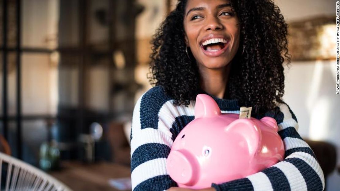 CNNE 768429 - black young woman hugging her pink piggy bank