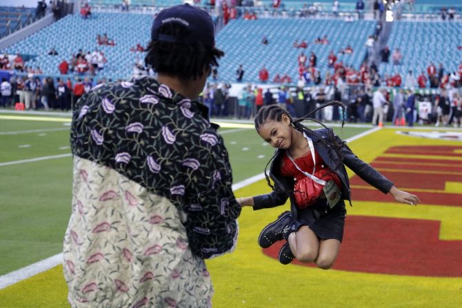 El rapero Jay-Z observa a su hija, Blue Ivy, saltar sobre el campo antes del partido. David J. Phillip / AP