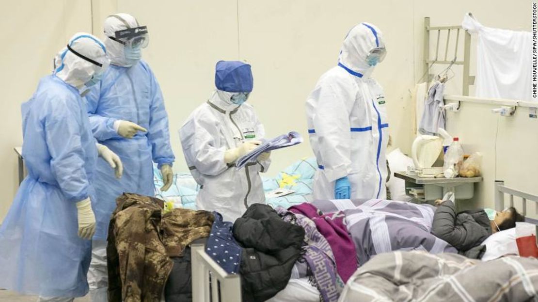 Personal médico verifica la condición de un paciente en un hospital convertido temporalmente para pacientes con coronavirus en Wuhan.