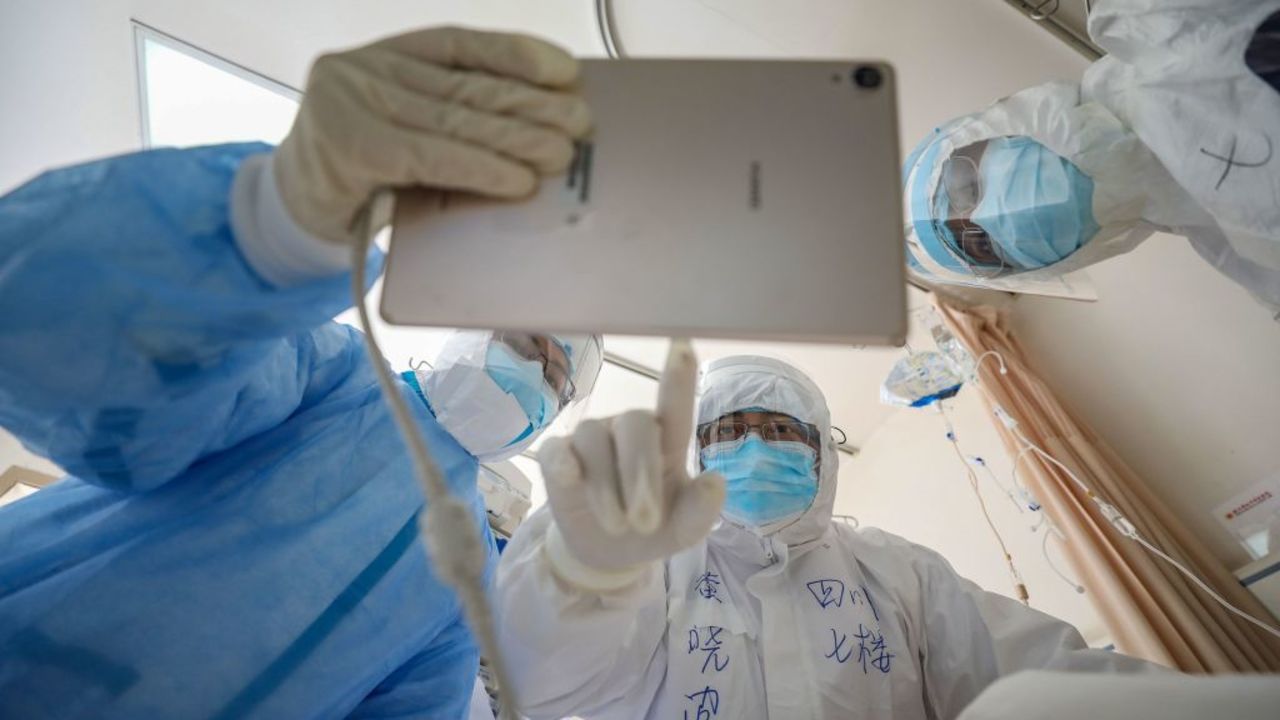 This photo taken on February 16, 2020 shows a doctor looking at an image as he checks a patient who is infected by the COVID-19 coronavirus at the Wuhan Red Cross Hospital in Wuhan in China's central Hubei province. - The death toll from the COVID-19 coronavirus epidemic jumped to 1,770 in China after 105 more people died, the National Health Commission said February 17. (Photo by STR / AFP) / China OUT