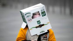 TOPSHOT - A boy wears a cardboard box on his head at the Shanghai Railway station in Shanghai on February 13, 2020. - The number of deaths and new cases from China's COVID-19 coronavirus outbreak spiked dramatically on February 13 after authorities changed the way they count infections in a move that will likely fuel speculation that the severity of the outbreak has been under-reported. (Photo by NOEL CELIS / AFP)