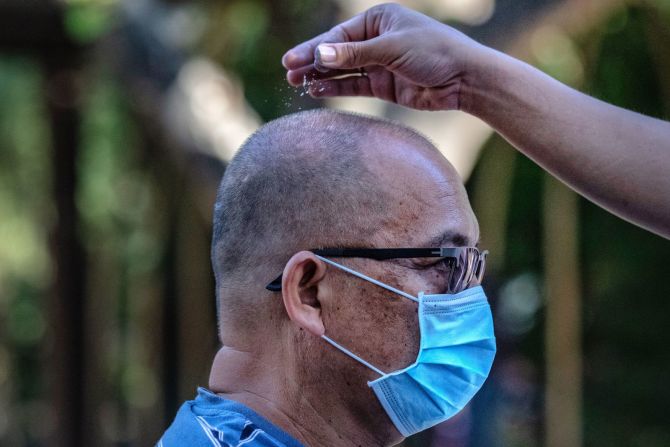 Un devoto católico usa una mascarilla facial mientras es rociado con cenizas durante los servicios del Miércoles de Ceniza en Paranaque, Filipinas, el 26 de febrero.