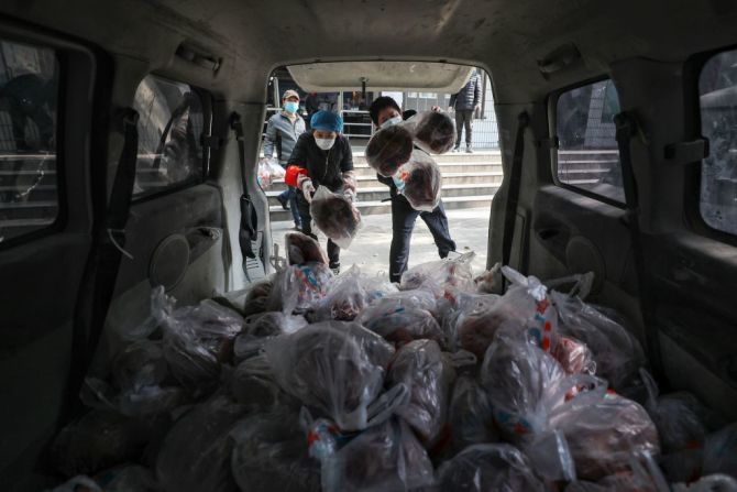 Los trabajadores de los supermercados se preparan para entregar bolsas de verduras a los residentes de Wuhan, China.