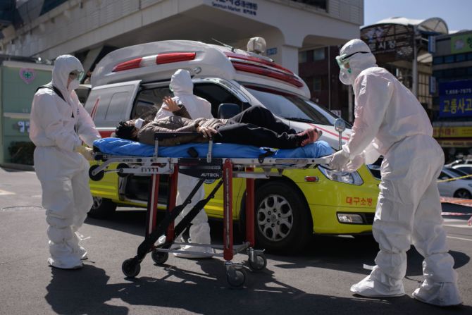 En esta foto tomada el 12 de marzo de 2020, los trabajadores médicos que usan ropa protectora contra el nuevo coronavirus COVID-19 atienden a una mujer con síntomas desconocidos que se sentía mal a su llegada al hospital de la Universidad de Keimyung en Daegu. Corea del Sur, que fue durante un tiempo el mayor brote de coronavirus fuera de China, vio a sus pacientes recién recuperados superar las infecciones recientes por primera vez el 13 de marzo, ya que informó su menor número de casos nuevos en tres semanas.