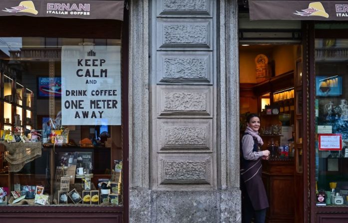 Una camarera observa un cartel que aconseja a los clientes que mantengan la distancia en un café el 10 de marzo de 2020 en el centro de Milán. Italia impuso restricciones nacionales sin precedentes a sus 60 millones de personas el 10 de marzo de 2020 para controlar el mortal coronavirus, ya que China señaló un gran progreso en su propia batalla contra la epidemia mundial.