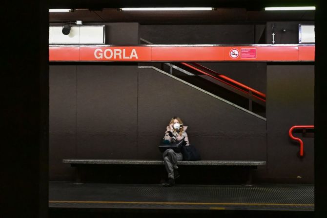 Una mujer que usa una máscara respiratoria habla por su teléfono inteligente mientras espera el metro en la estación de metro Gorla en el centro de Milán el 10 de marzo de 2020.