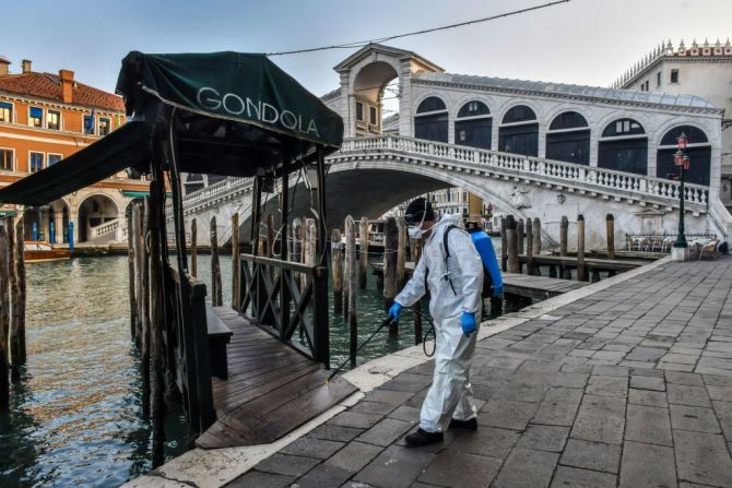 Un empleado de la empresa municipal Veritas rocía desinfectante en áreas públicas en el Puente de Rialto en Venecia el 11 de marzo de 2020, como parte de las medidas de precaución contra la propagación del nuevo coronavirus COVID-19, un día después de que Italia impuso restricciones nacionales sin precedentes en sus 60 millones de personas el martes para controlar el mortal coronavirus COVID-19.