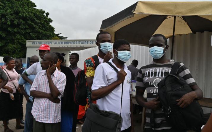 Las personas usan máscaras protectoras mientras esperan en una parada de autobús afuera del hospital universitario de Treichville, el 11 de marzo de 2020, donde se confirmó el primer caso de nuevo coronavirus en Costa de Marfil.