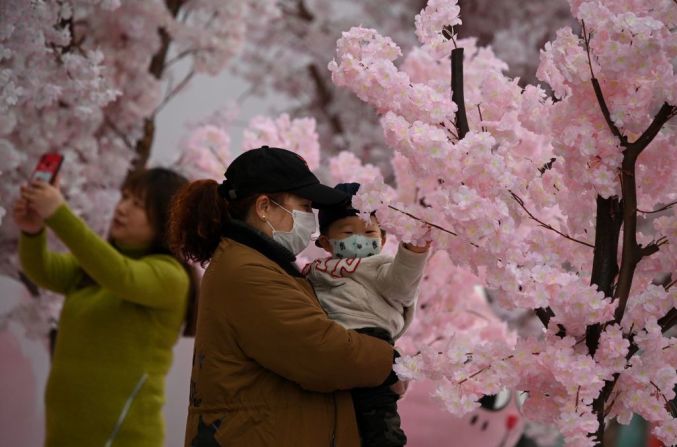 Personas con usando máscaras faciales admiran los cerezos cerca de un centro comercial en Nanjing, provincia de Jiangsu, en el este de China.