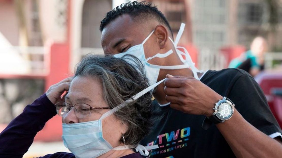 Un hombre coloca a una máscara facial a una mujer en San José, Costa Rica.