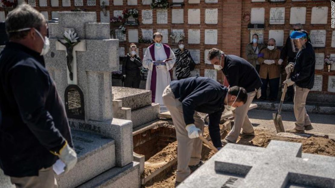 Un sacerdote y los familiares de una víctima mortal de covid-19 llevan a cabo una ceremonia fúnebre en el cementerio de La Almudena, en Madrid, España, el 28 de marzo de 2020.