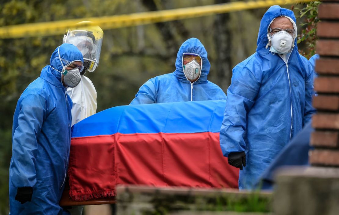 Trabajadores del cementerio usan trajes protectores mientras llevan el ataúd del médico colombiano William Gutiérrez, quien murió de covid-19 en Bogotá el 12 de abril de 2020. Crédito: JUAN BARRETO/AFP via Getty Images