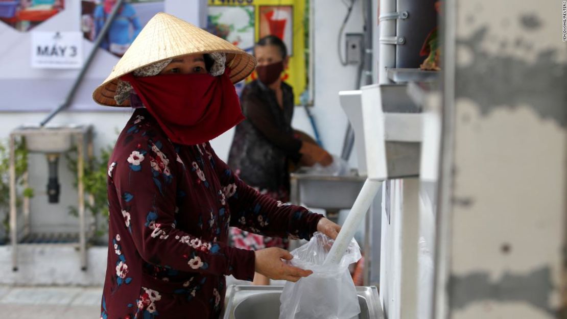 Una mujer llena una bolsa plástica con arroz de un cajero automático de arroz 24/7 en Ho Chin Minh, Vietnam, el 11 de abril de 2020.